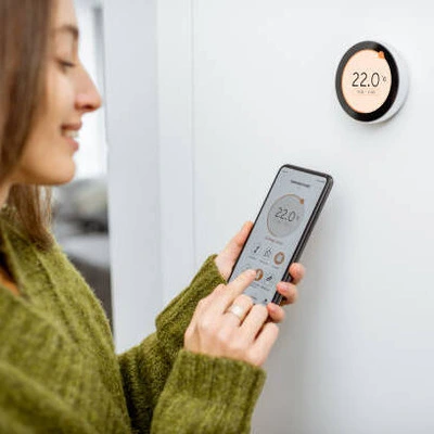 reglage_temperature_telephone-_1_ femme qui règle le radiateur électrique avec son smartphone